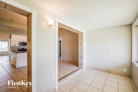A spacious room with a tiled floor and a doorway leading to another room.