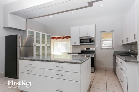 A kitchen with white cabinets and a black refrigerator.