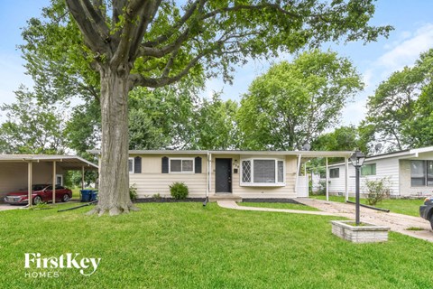 a white house with a large tree in the yard
