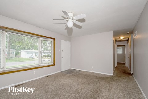an empty living room with a ceiling fan and a large window