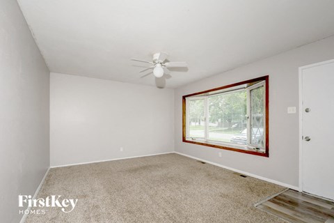 an empty room with a window and a ceiling fan
