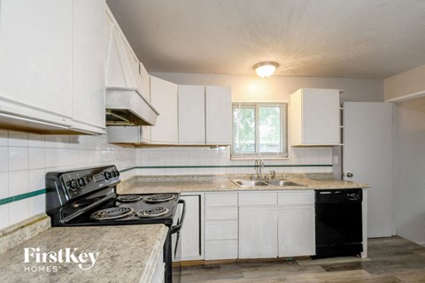 a kitchen with white cabinets and a stove and a sink