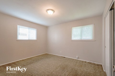 a bedroom with a carpeted floor and two windows