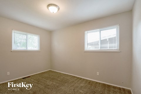 an empty room with two windows and a carpet