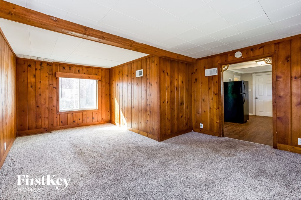 the living room of a house with carpet and wood paneling