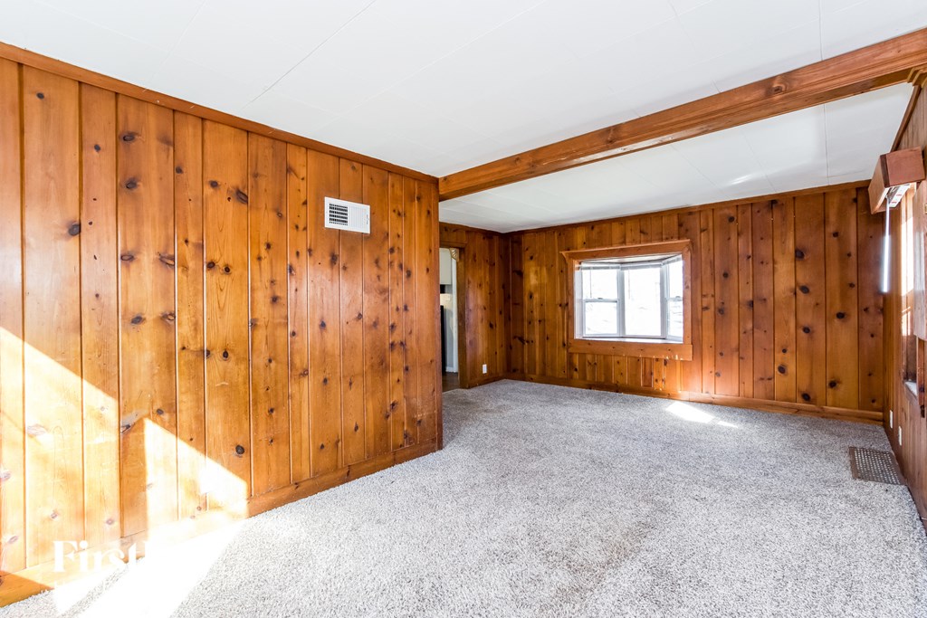 an empty room with wood paneling and a carpet floor