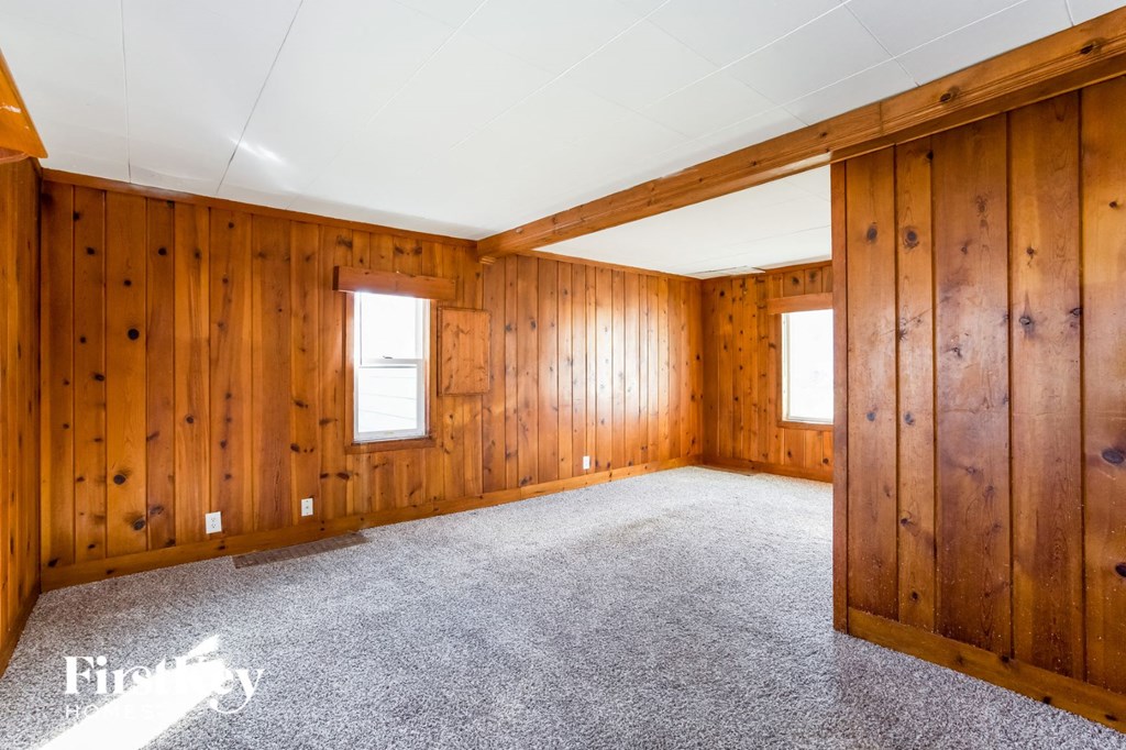 bedroom with carpeted floor and wood paneled walls in a home