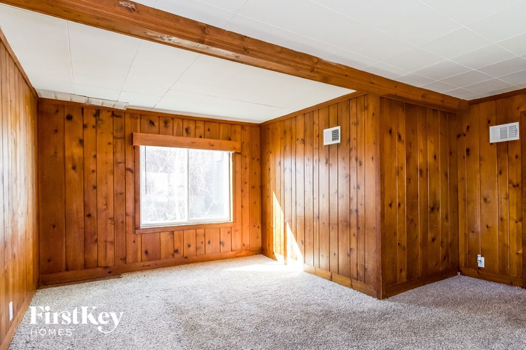 the living room of a house with wood paneling and a window