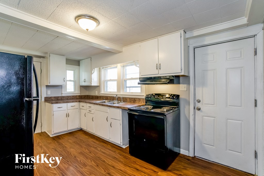 a kitchen with white cabinets and black appliances