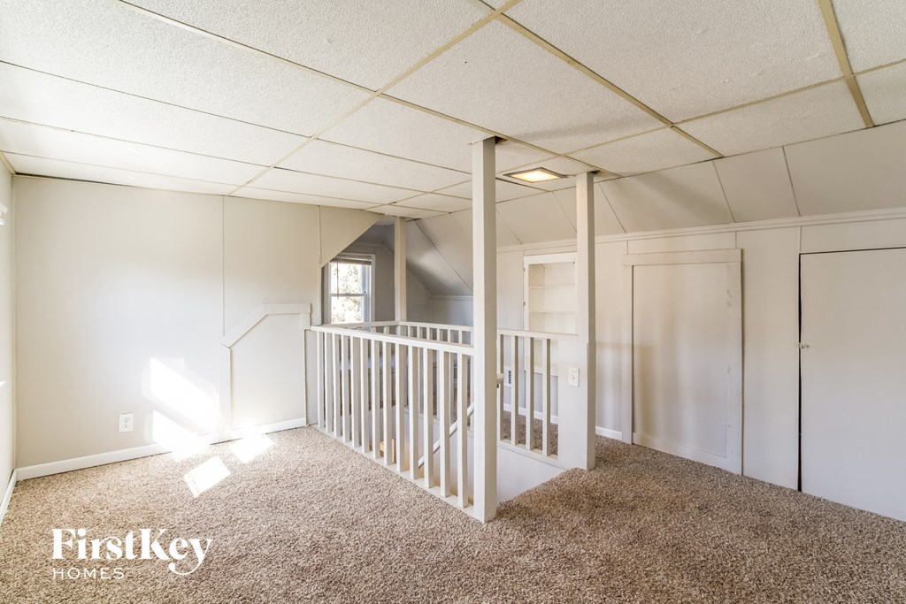 a small white room with a white staircase and a hallway with white walls and carpet