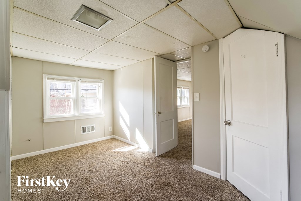 a bedroom with white walls and carpet and a door to a hallway