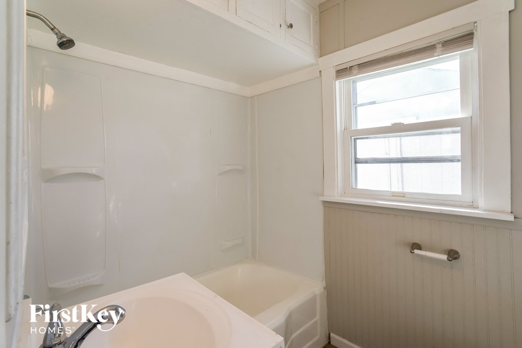 a small bathroom with a tub and a sink and a window