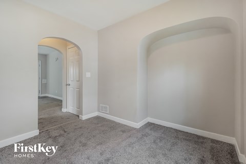 a living room with white walls and carpet and archways