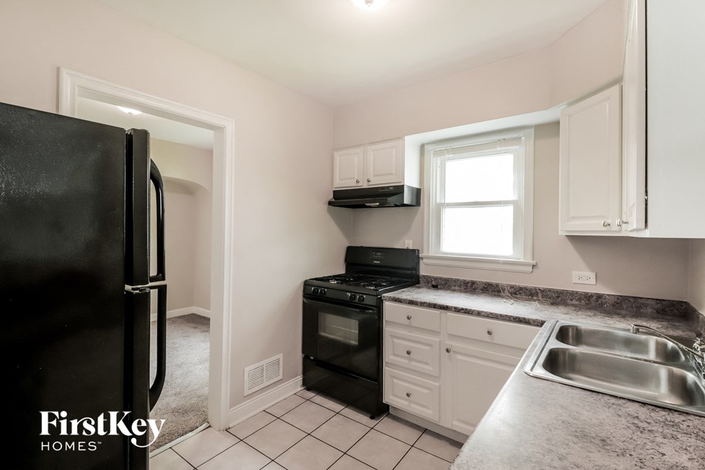 a kitchen with white cabinets and black appliances and a black refrigerator