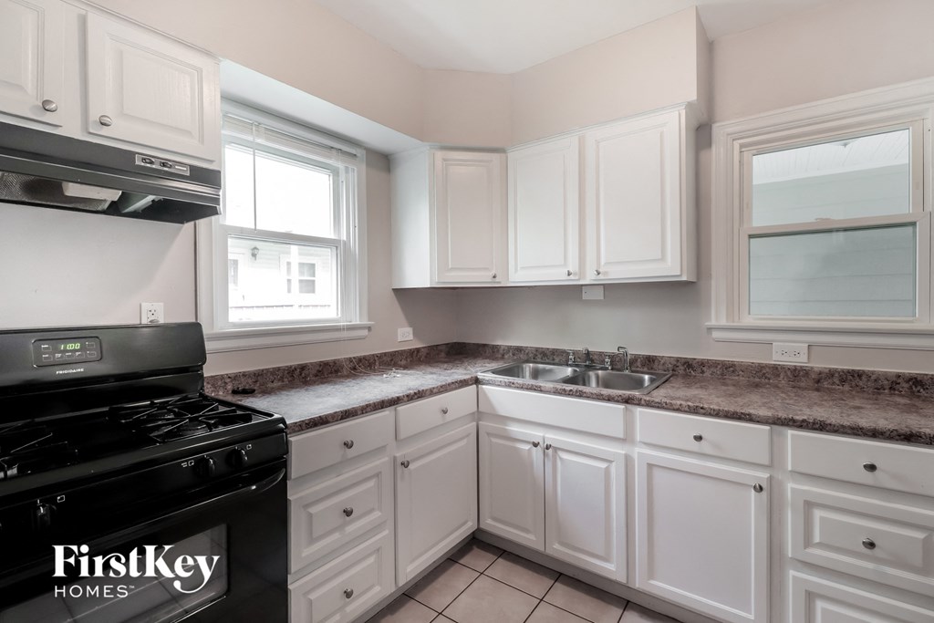 a kitchen with white cabinets and a stove and a sink