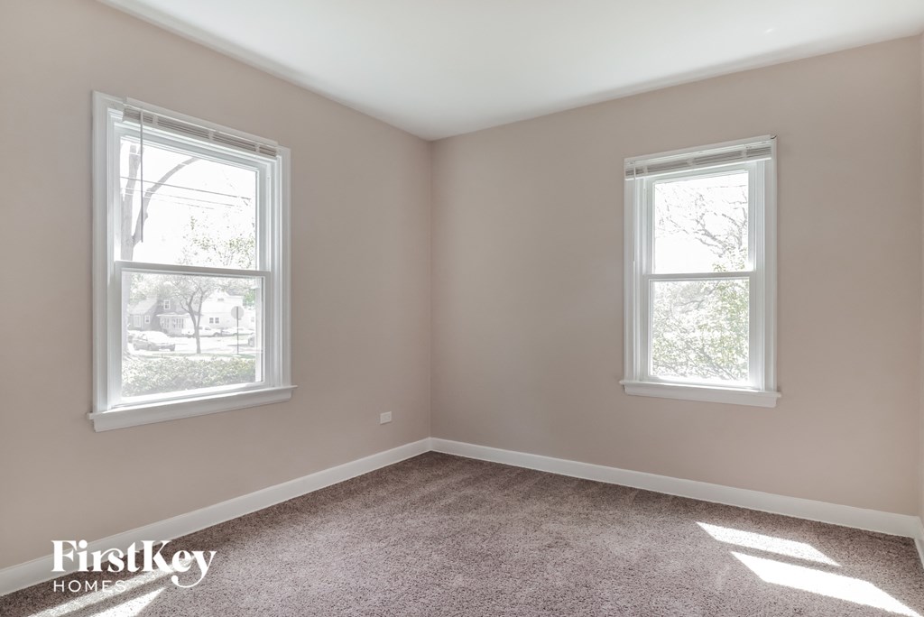 a bedroom with two windows and a carpeted floor