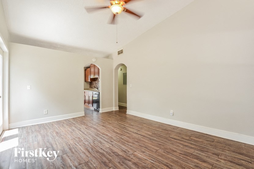 the living room and dining room of an empty house with a ceiling fan