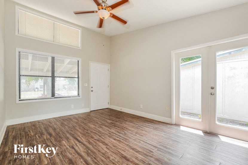 an empty living room with a ceiling fan and windows