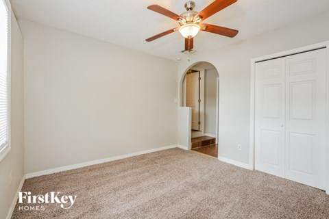 a spacious living room with carpet and a ceiling fan