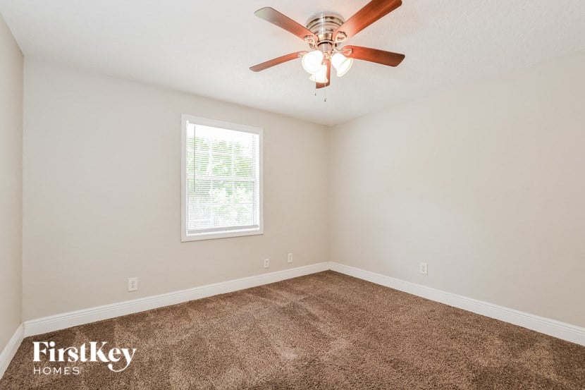 an empty bedroom with a ceiling fan and a window