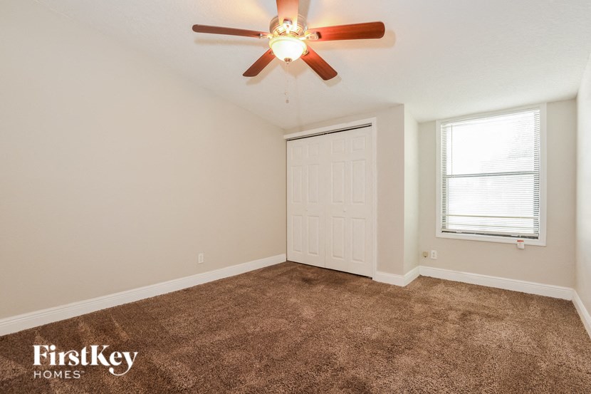 an empty room with a ceiling fan and a window
