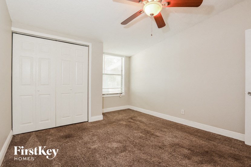 an empty bedroom with a ceiling fan and a closet