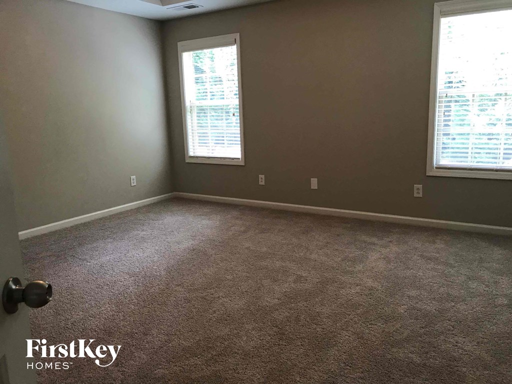 a room with a carpeted floor and two windows