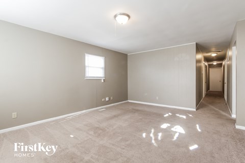 a empty living room with a door to a hallway and a window