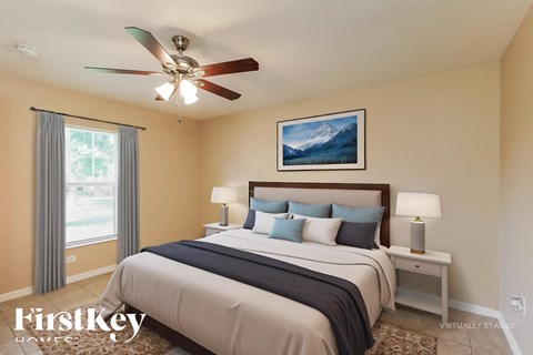 A bedroom with a large bed and a ceiling fan.