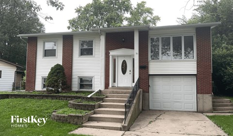 A two-story house with a white garage door and a brick pillar.