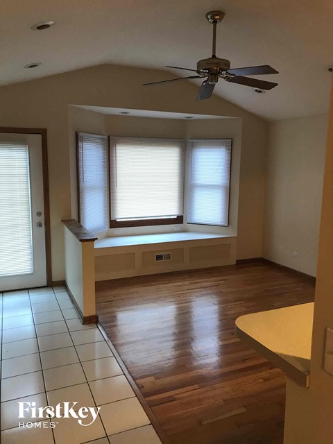 A room with a ceiling fan and a window with blinds.