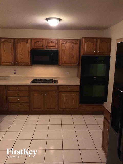 A kitchen with wooden cabinets and black appliances.