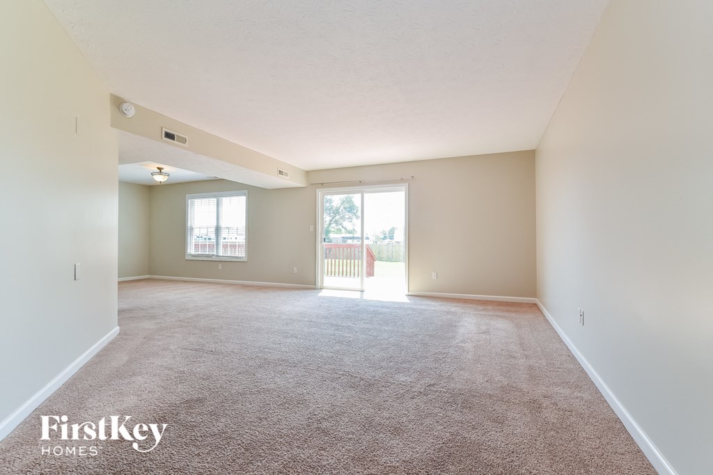 the living room of an empty house with carpet and a large window