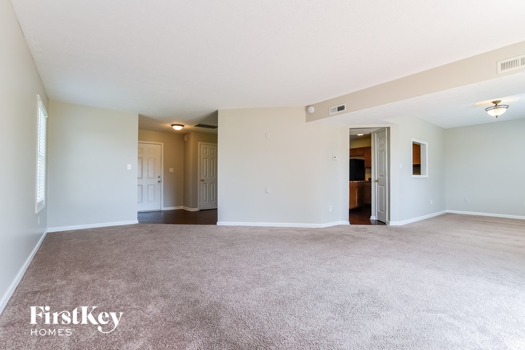 an empty living room with carpet and white walls
