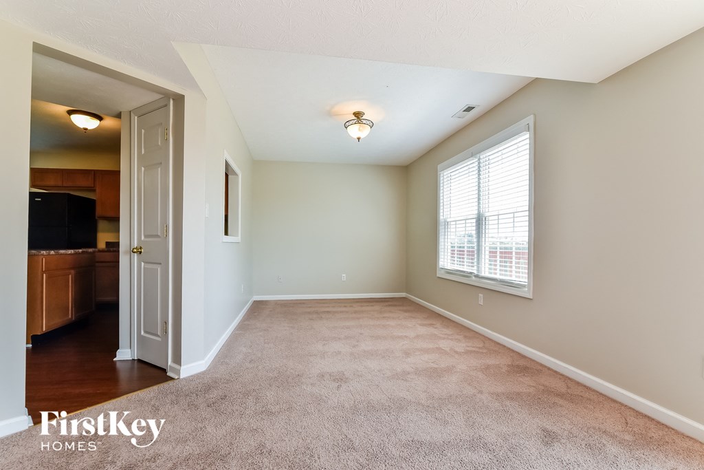 an empty living room with a large window and carpet
