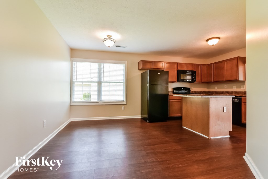an empty kitchen with wooden cabinets and a black refrigerator