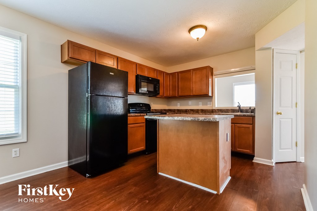 a kitchen with wooden cabinets and a black refrigerator
