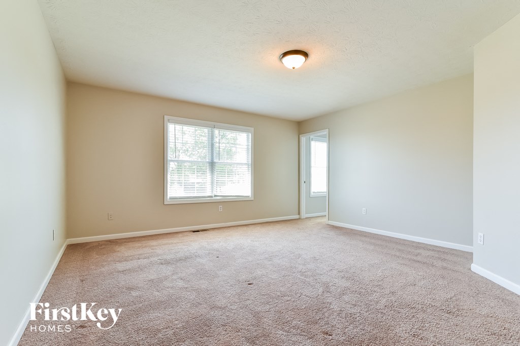 a spacious living room with carpet and a window