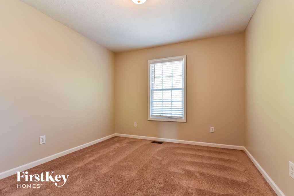the spacious living room with beige carpet and a window