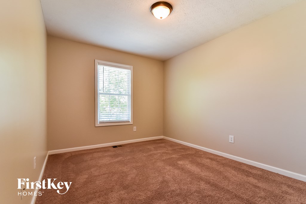 the spacious living room with carpeting and a window