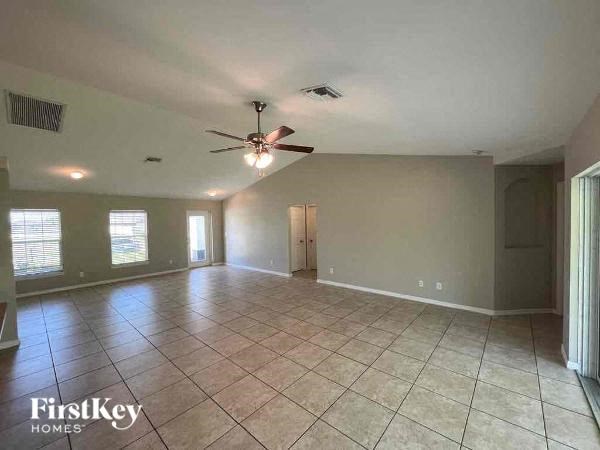 an empty living room with a ceiling fan and tiled floors