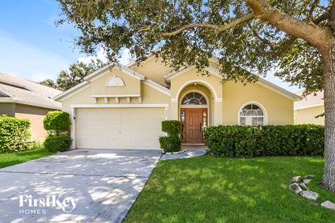 A house with a garage and a tree in front of it.