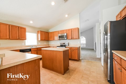 A kitchen with wooden cabinets and a black refrigerator.