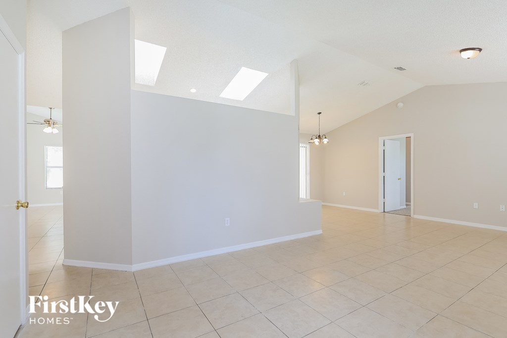 the living room and dining room with white walls and tile flooring