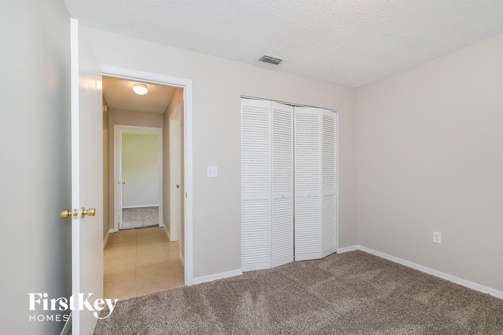 an empty living room with a hallway to a closet and a door to a bathroom