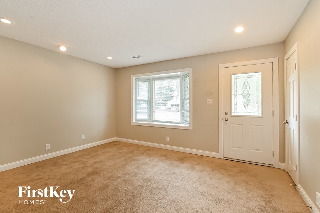 an empty living room with a white door and a window