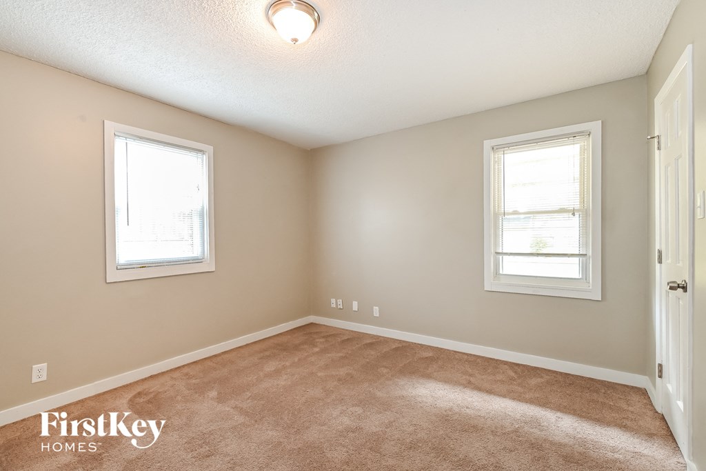 a bedroom with a carpeted floor and two windows