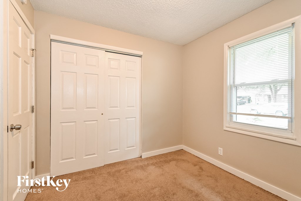 the bedroom of a home with a white door and a window