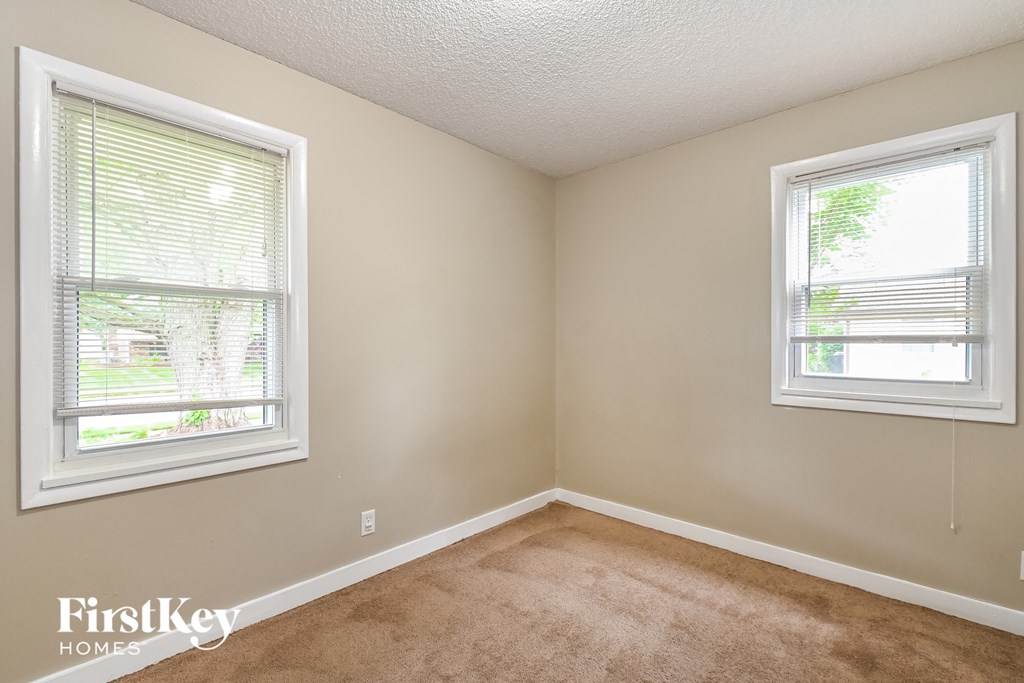 a bedroom with two windows and a carpeted floor