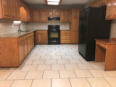 A kitchen with wooden cabinets and black appliances.